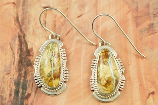 Genuine Boulder Turquoise set in Sterling Silver French Wire Earrings. The cabachons are of Boulder Turquoise, you can see the veins of Turquoise running through the host rock. The Boulder Turquoise Mine is located in northeast Nevada. It was discovered in 1970 by a Shoshone sheep herder. Production is small due to the remote location and winter weather. Boulder Turquoise is valued for both it's beauty and rarity. Every stone is unique. Created by Navajo Artist Larson Lee. Signed by the artist.